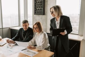 SIA Door Supervisor Refresher - A group of business professionals discussing documents at a conference table in a modern office environment.