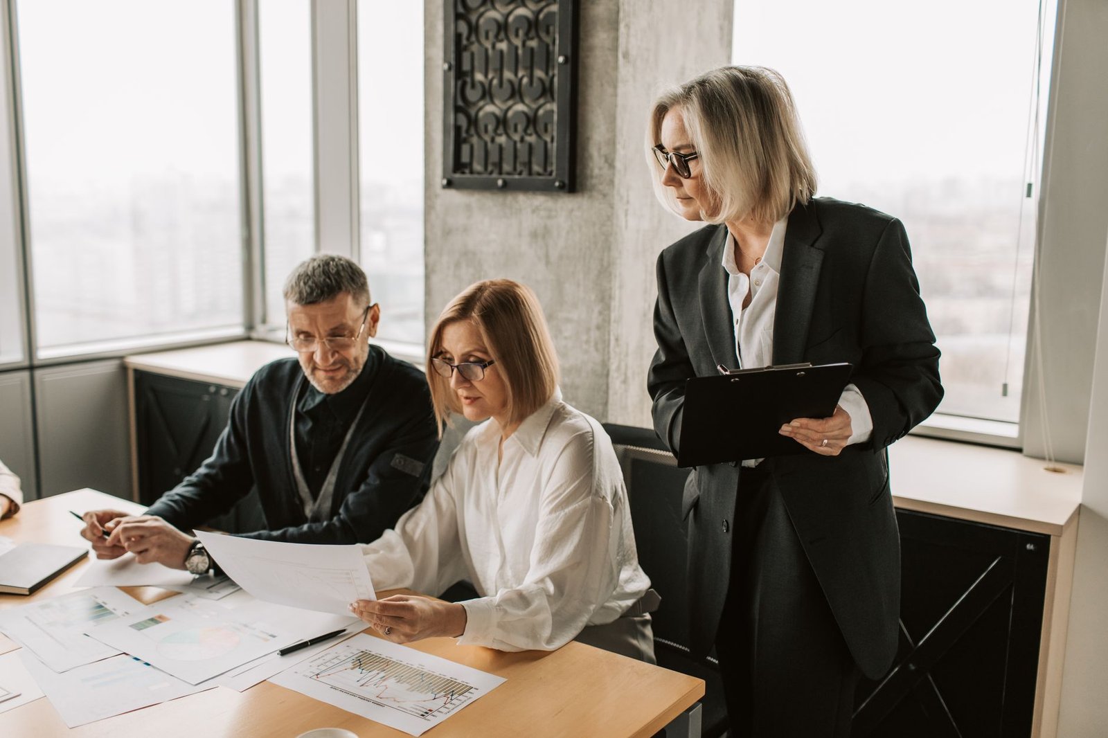 SIA Door Supervisor Refresher - A group of business professionals discussing documents at a conference table in a modern office environment.