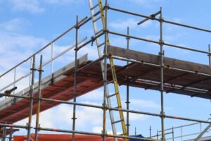 CSCS Construction Course - Detailed view of a construction site scaffolding structure and ladder against a bright blue sky.
