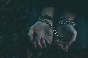 Modern Slavery Awareness Certification - A dramatic close-up image of hands bound by silver chains, symbolizing captivity or struggle.
