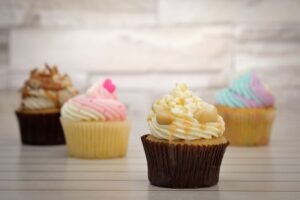 Cupcake Academy: Introduction to Baking - Deliciously decorated cupcakes with colorful frosting displayed on a wooden surface, perfect for dessert lovers.