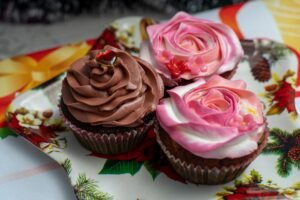 Cupcake Academy: Introduction to Cake Decorating - Close-up of beautifully decorated cupcakes with rose and chocolate frosting on a festive platter.