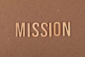 Strategic Planning / Mission Statement Certification - Wooden letters spelling 'MISSION' on textured cardboard background, emphasizing goals and purpose.