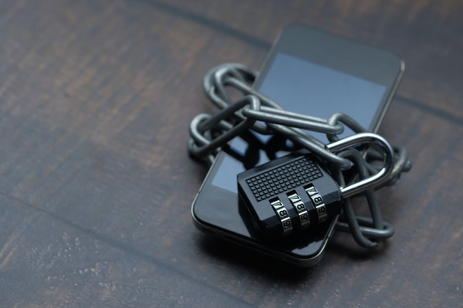 Keeping Our Data Secure - Close-up of a smartphone wrapped in a chain with a padlock, symbolizing strong security.