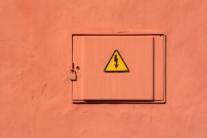 Hazard Identification and Risk Control Certification - Bright yellow high voltage warning sign on a locked electrical box.