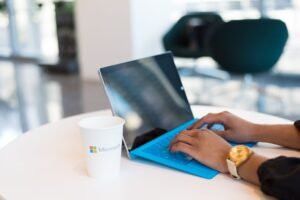Microsoft Outlook Certificate Level 2 - Hands typing on a blue keyboard with a branded cup on a table.