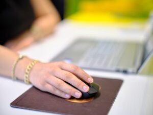 Think Before You Click - A person using a wireless mouse at a desk, perfect for business or technology themes.