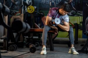 Finding Motivation to Get Fit and Stay Fit Certification - A muscular man working out in a gym, lifting a dumbbell for strength training.
