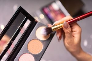 Contour and Highlighting Certificate - Hand with manicured nails using a makeup brush on a palette for cosmetic application.