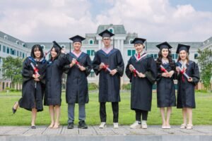 Recruitment Diploma - Group of diverse young graduates in gowns holding diplomas outdoors in front of a university building.