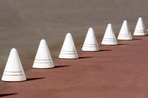 Handling Objections & Overcoming Barriers to Sales Certification - White traffic cones line a red and gray road surface, creating a pattern.