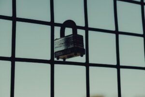Impacts of Weak Security - Close-up of a steel padlock on a mesh fence, symbolizing protection and security.