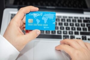 Identity Theft Awareness Certification - Person holding credit card near laptop for online shopping, emphasizing secure online transactions.