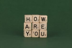 How to Build Resilience Certification - Wooden Scrabble letter blocks spelling 'how are you' on a green background.