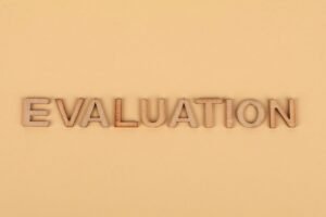 Training Delivery and Evaluation Certification - Wooden letter blocks arranged to spell 'evaluation' on a beige background.