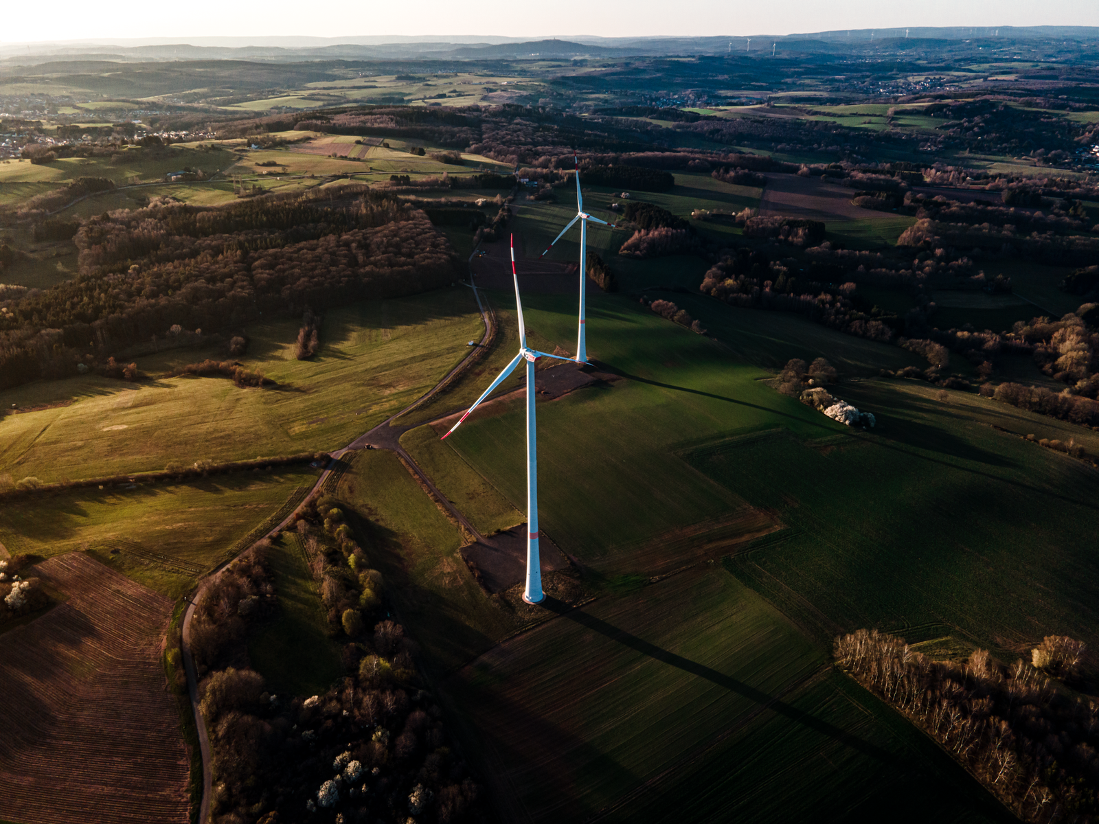 Carbon Reduction Measures and Becoming Green Certification - Aerial landscape of wind turbines in green fields, promoting renewable energy in Schiffweiler, Germany.