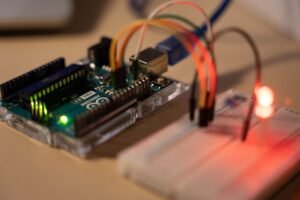 Introduction to IoT-Internet of Things Certification - Close-up of Arduino microcontroller connected to a breadboard with a glowing LED.