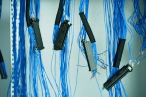 Cable and Wire Management Awareness Certification - Close-up of blue ethernet cables hanging in a data center, highlighting technology connections.
