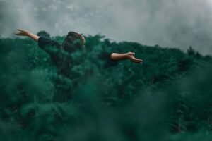 EFT – Emotional Freedom Technique Certification - A woman with open arms enjoying freedom in a foggy green landscape.