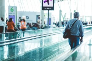Remote Worker & Business Travel Security Certification - A bustling airport scene with travelers on a moving walkway in a modern terminal.