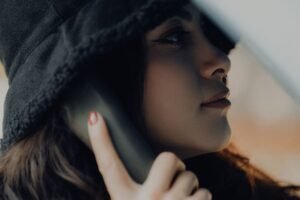 Cold Calling Certification - A close-up of a woman wearing a hat, holding a phone to her ear.