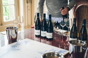 Introduction to Being a Sommelier Certification - A sommelier pouring wine from bottles on a restaurant table with glasses and buckets.
