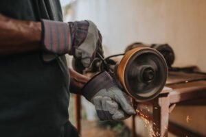 Abrasive Wheels Certification - A craftsman using a grinder with sparks flying indoors, showcasing skill and precision.