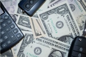 Key Account Management Certification - An arrangement of US dollar bills, car keys, and a calculator representing finance and investment concepts.