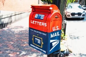 Communication Basics Certification - Vibrant U.S. mailbox on a city sidewalk with a parked car, conveying a classic urban scene.
