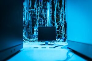 IT Certification Level 2 - A complex network of cables in a data center with a monitor in the foreground.