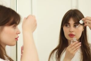 Skincare Certificate - A young woman applying skincare serum in front of a mirror indoors. Perfect for beauty and self-care themes.