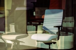 Ergonomics – Steps to Reduce Workplace Related Injuries Certification - Contemporary office chairs displayed behind glass, offering modern ergonomic solutions for workspace.