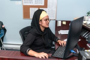 Admin, PA and Secretarial Certification - Middle Eastern woman in hijab using computer in office setting, focusing on work.