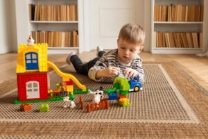 Play Therapy Certification - Young boy engaged in imaginative block play on a carpeted floor indoors.
