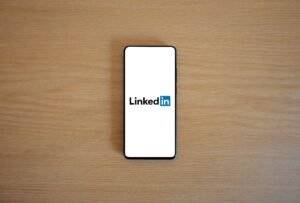 LinkedIn for Business Certification - Top view of a smartphone displaying the LinkedIn logo on a wooden surface.