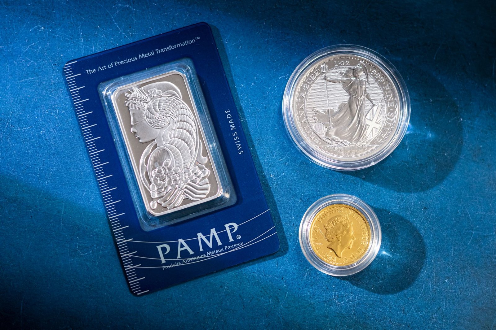 Investing in Gold and Silver Certification - Silver bar and coins on blue surface, highlighting investment and collectible value.