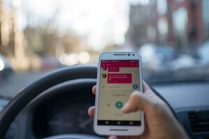 The Dangers of Texting While Walking Certification - A person texting on a smartphone while driving an automobile in a city, illustrating distracted driving and technology use.