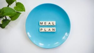 Meal Planning Certification - Innovative meal planning concept using alphabet tiles on a blue plate with green leaves.