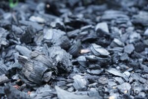 Carbon Monoxide Awareness Certification - Detailed close-up of rough charcoal pieces spread outdoors, showcasing texture.