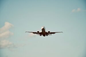 Travel and Tourism Certification Level 2 - A commercial airplane in flight against a clear blue sky, representing air travel and transportation.