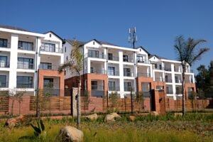 Property Development Certification - Contemporary apartment complex with garden, featuring white facade and red brick accents.