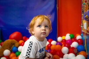 Adverse Childhood Experiences Certification - Adorable toddler exploring a vibrant indoor ball pit. Ideal for playful and family-themed content.