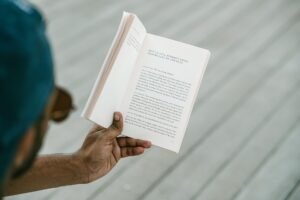 How to Programme Your Mind for Success Certification - A person engrossed in reading an inspirational book outdoors on a sunny day.