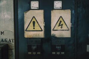 Electrical Safety in the Workplace Certification - Close-up of industrial warning signs on an aged electrical panel.