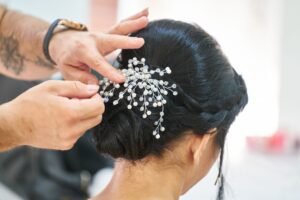 Bridal Hair Certificate - Photograph of a hairstylist arranging an elegant updo embellished with delicate decorative pins in a professional studio.