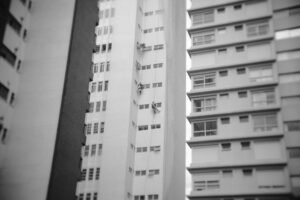 Working at Height Awareness Certification - High-rise building with workers performing maintenance, captured in a classic monochrome style.