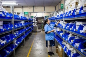 Third Party Suppliers - A worker in a warehouse organizing inventory on shelves with blue bins.