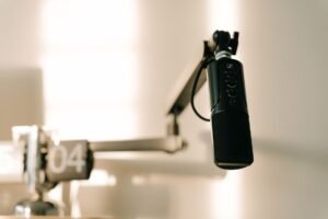 Introduction to Podcasting Certificate - A sleek professional microphone on a boom arm in a minimalist studio.