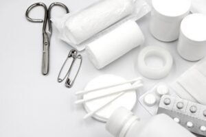 Emergency First Aid in the Workplace Certification - A detailed flat lay of essential first aid supplies including bandages, scissors, and pills.