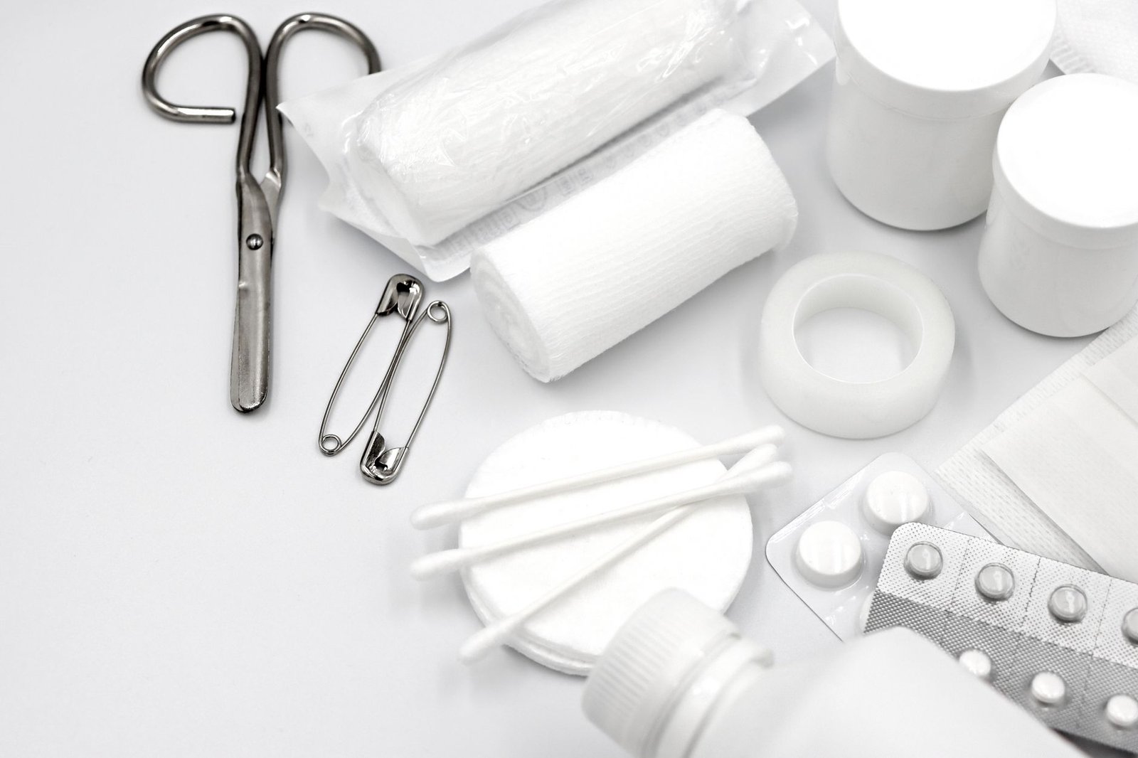 Emergency First Aid in the Workplace Certification - A detailed flat lay of essential first aid supplies including bandages, scissors, and pills.